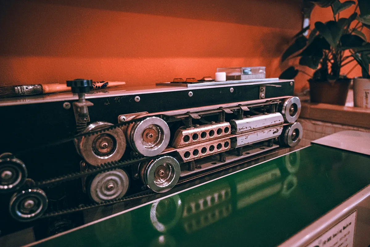 Exposed rollers, gears and belt on industrial machinery.